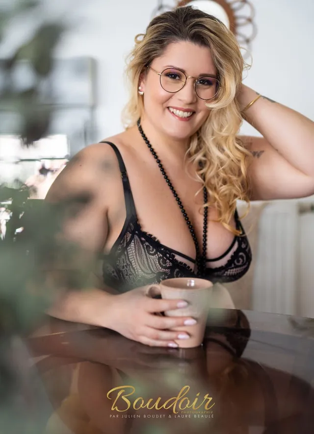 Cécile souriante avec lunettes, lingerie noire et tasse de thé
